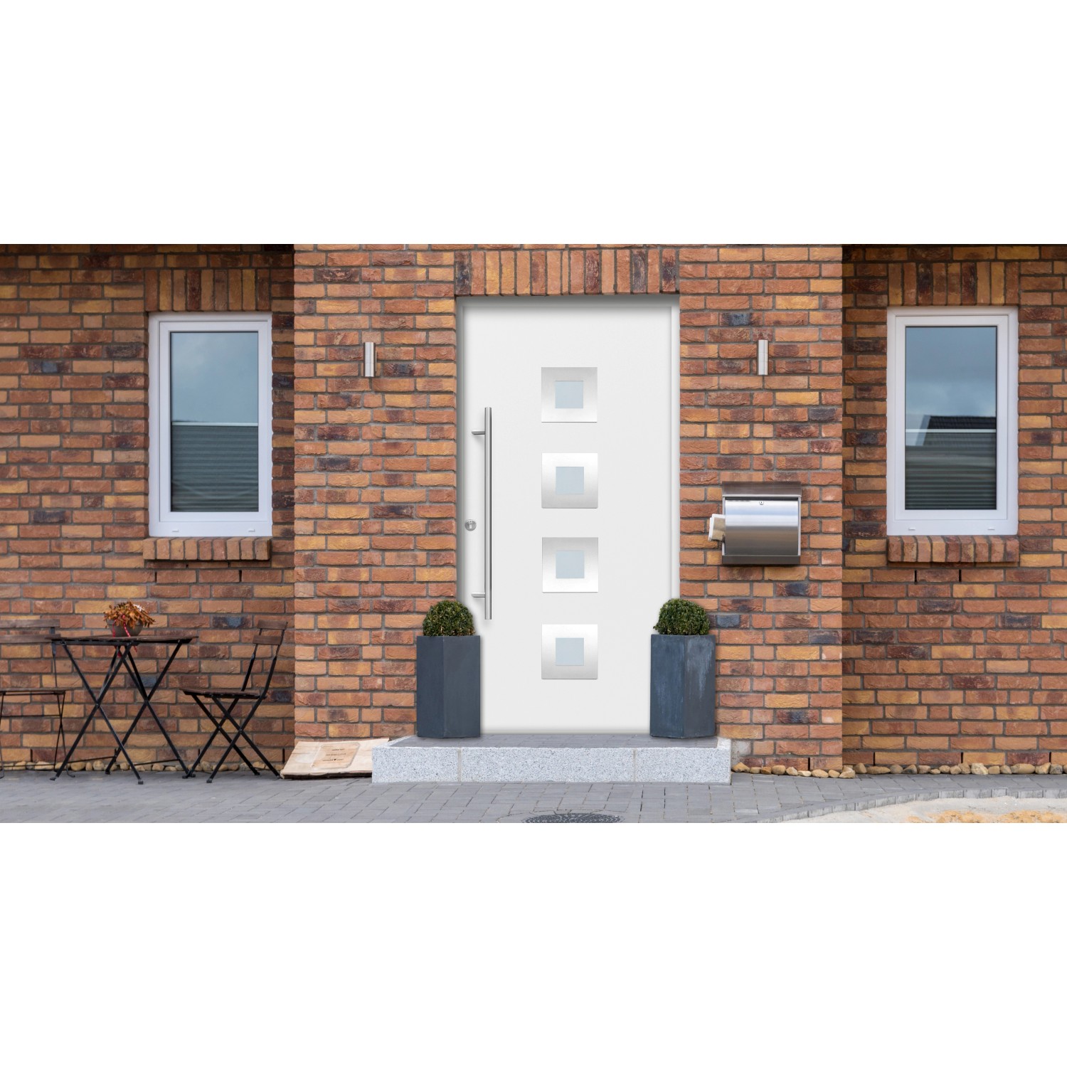 Weiße Haustür Thermospace Wien Prime mit Edelstahlgriff und quadratischen Glaseinsätzen vor Backsteinmauer.