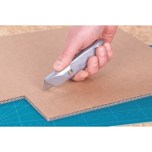 Hand schneidet Pappe mit wolfcraft Trapezklingen-Messer. Silbernes Gehäuse, feststehende Klinge.