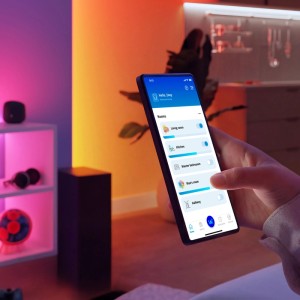 Hand steuert Philips Smarte Leuchten per WiZ App auf Smartphone. Bunte Beleuchtung im Raum. Smart-Dial-Schalter.
