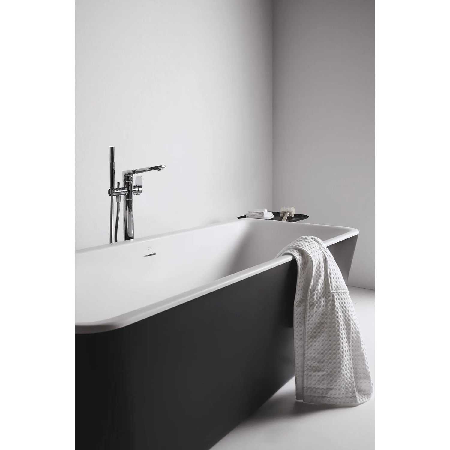Freistehende Ideal Standard Badewanne Dea, oval, 170x75 cm, schwarz matt mit Armatur und Handtuch.
