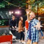 Roter Axi Kühlwagen mit Tischfußball (65 l) auf einer Party mit feiernden Menschen.