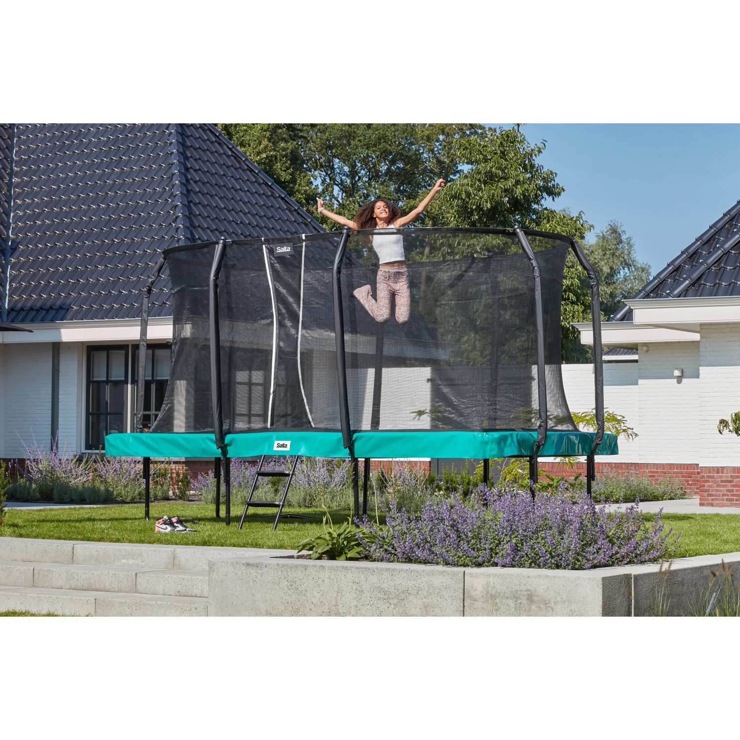 Grünes Salta First Class Gartentrampolin 366x214 cm mit Sicherheitsnetz und Leiter, springende Person.