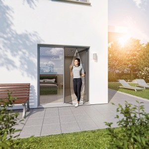 Windhager Türvorhang Magnet, schwarz, 95x215cm. Frau geht durch den Insektenschutz der Fliegengittertür.