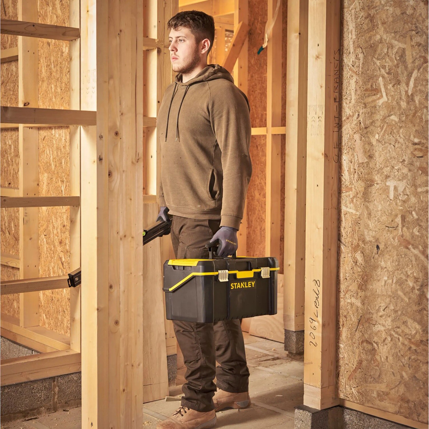 Stanley Werkzeugbox Cantilever Essential 19, 3-Etagen, getragen von Handwerker in Rohbau.