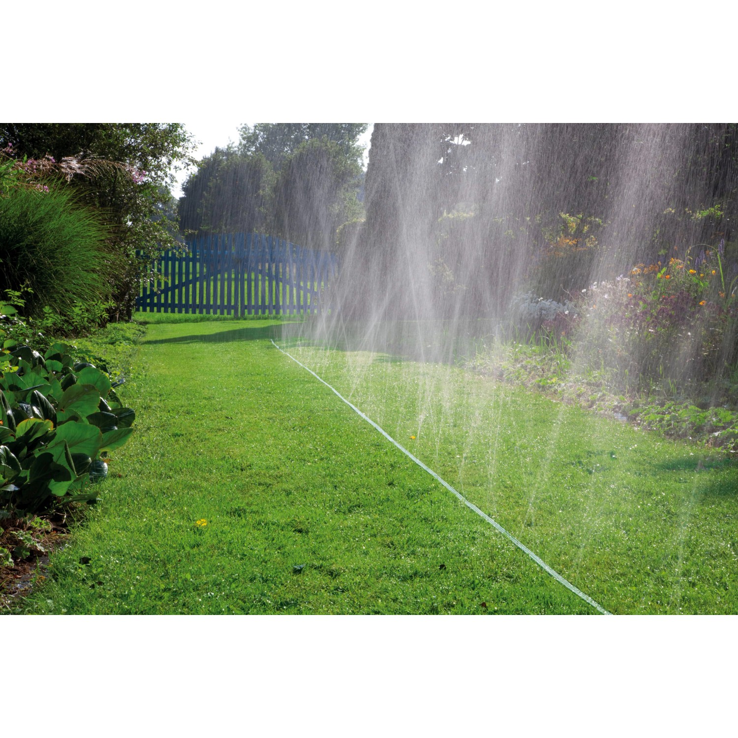 Gardena Schlauch-Regner 15m bewässert Rasenfläche im Garten mit feinem Sprühregen.