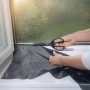 Zuschneiden des anthrazitfarbenen Tesa Pollenschutzgitters am Fenster.