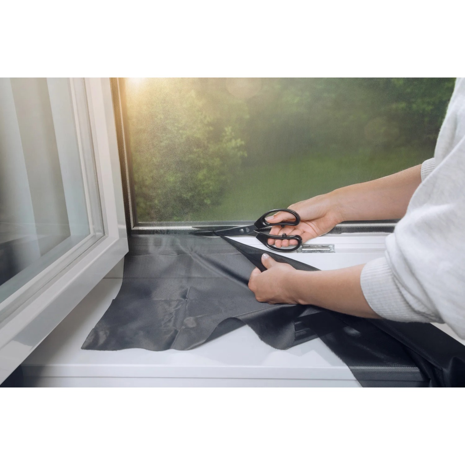 Zuschneiden des anthrazitfarbenen Tesa Pollenschutzgitters am Fenster.