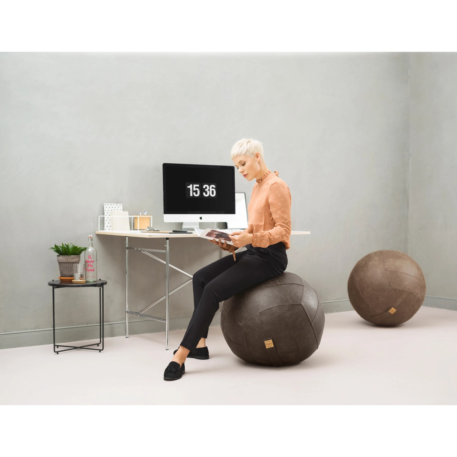 Brauner Sitting Ball Hocker Frankie (150 l) im Wohnraum mit Person.