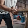 Mann sägt Holz mit Bosch Professional Akku-Stichsäge GST 18 V-125 S. Blaue kabellose Stichsäge im Einsatz.