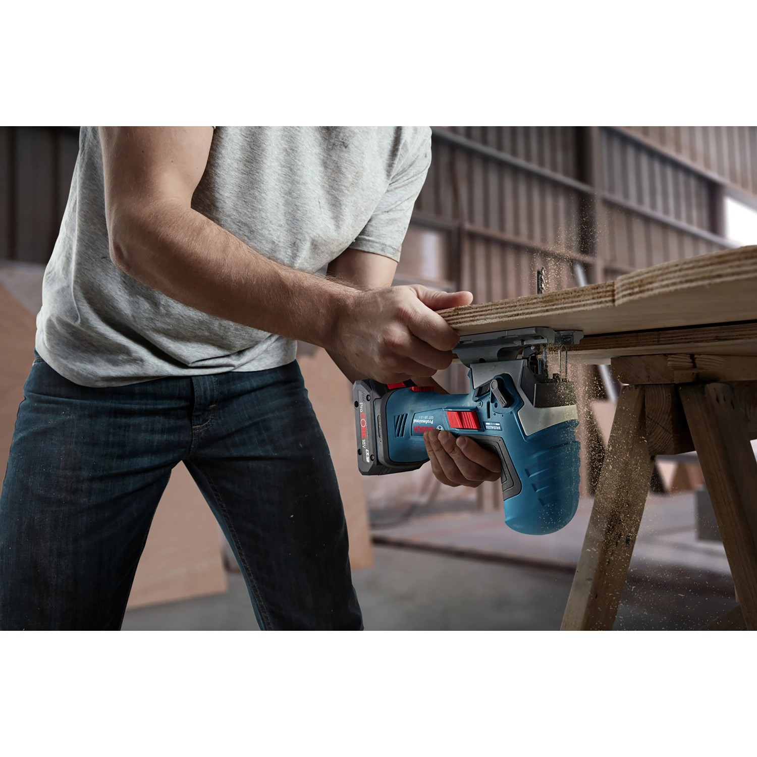 Mann sägt Holz mit Bosch Professional Akku-Stichsäge GST 18 V-125 S. Blaue kabellose Stichsäge im Einsatz.