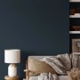Wand in dunklem Blau mit V&CO Premium-Innenfarbe Mitternachtshimmel, kombiniert mit Lampe und Sofa.