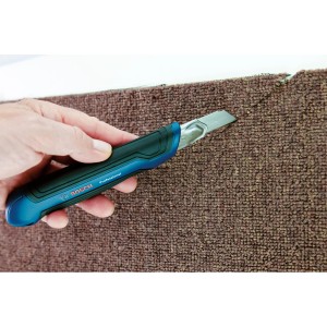 Bosch Professional Cuttermesser schneidet Teppich. Messer mit 18 mm Klinge und blau-schwarzem Griff.