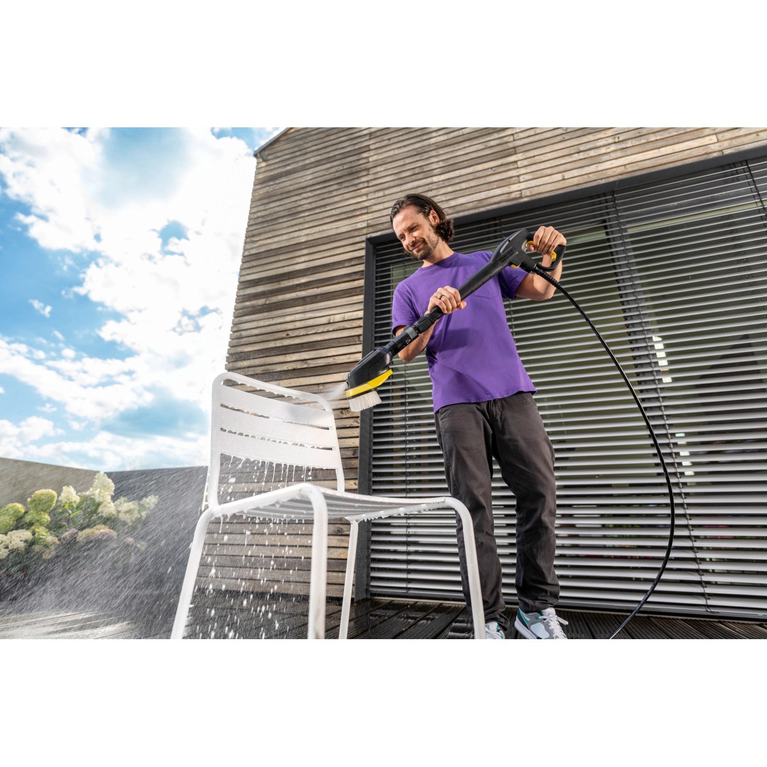 Mann reinigt Stuhl mit Kärcher WB 7 Plus 3-in-1 Waschbürste. Die Bürste hat Schaumdüse, Hochdruckstrahl und weiche Borsten.