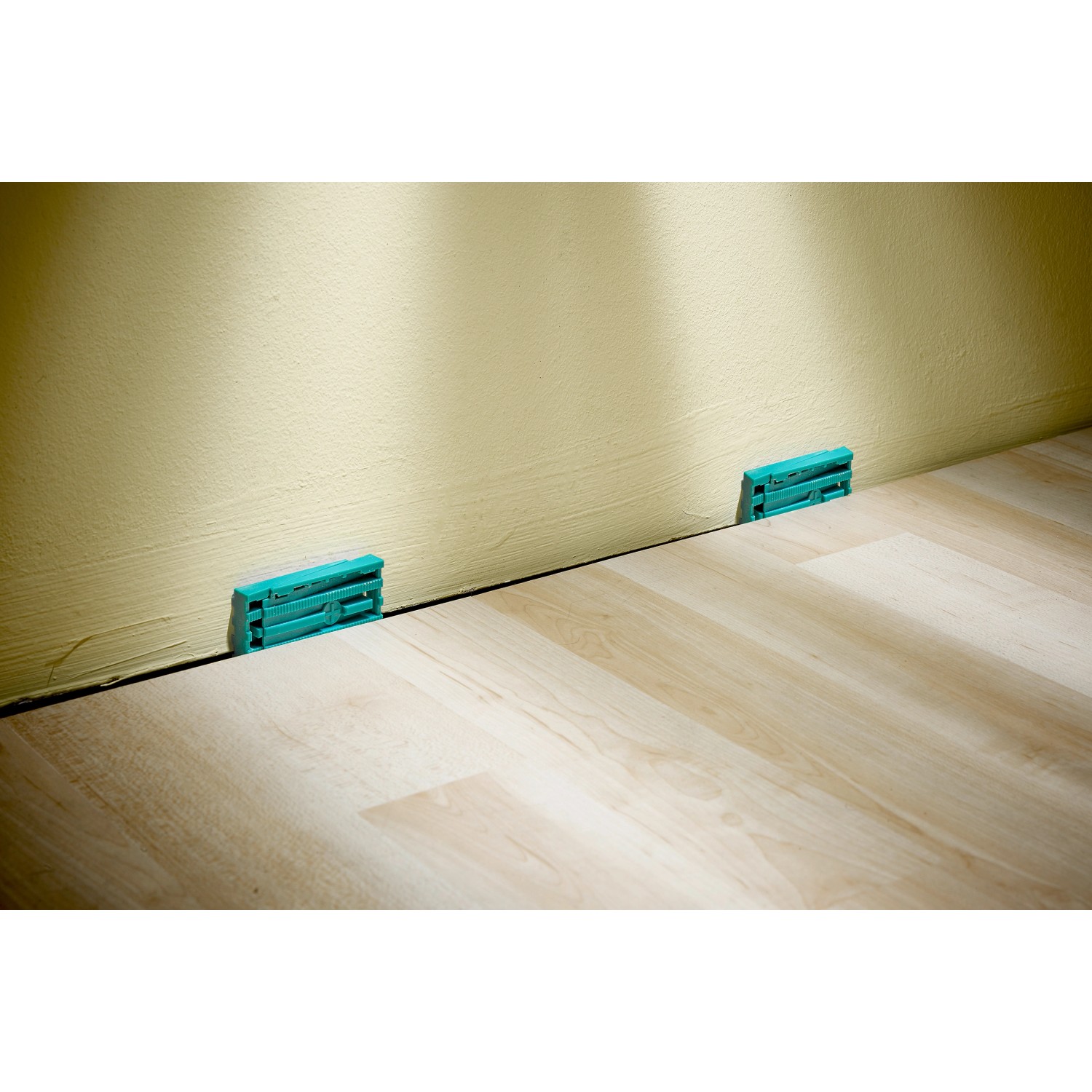 Verlege-Set: Laminat- und Designboden mit Keilen für Dehnungsfugen an der Wand.