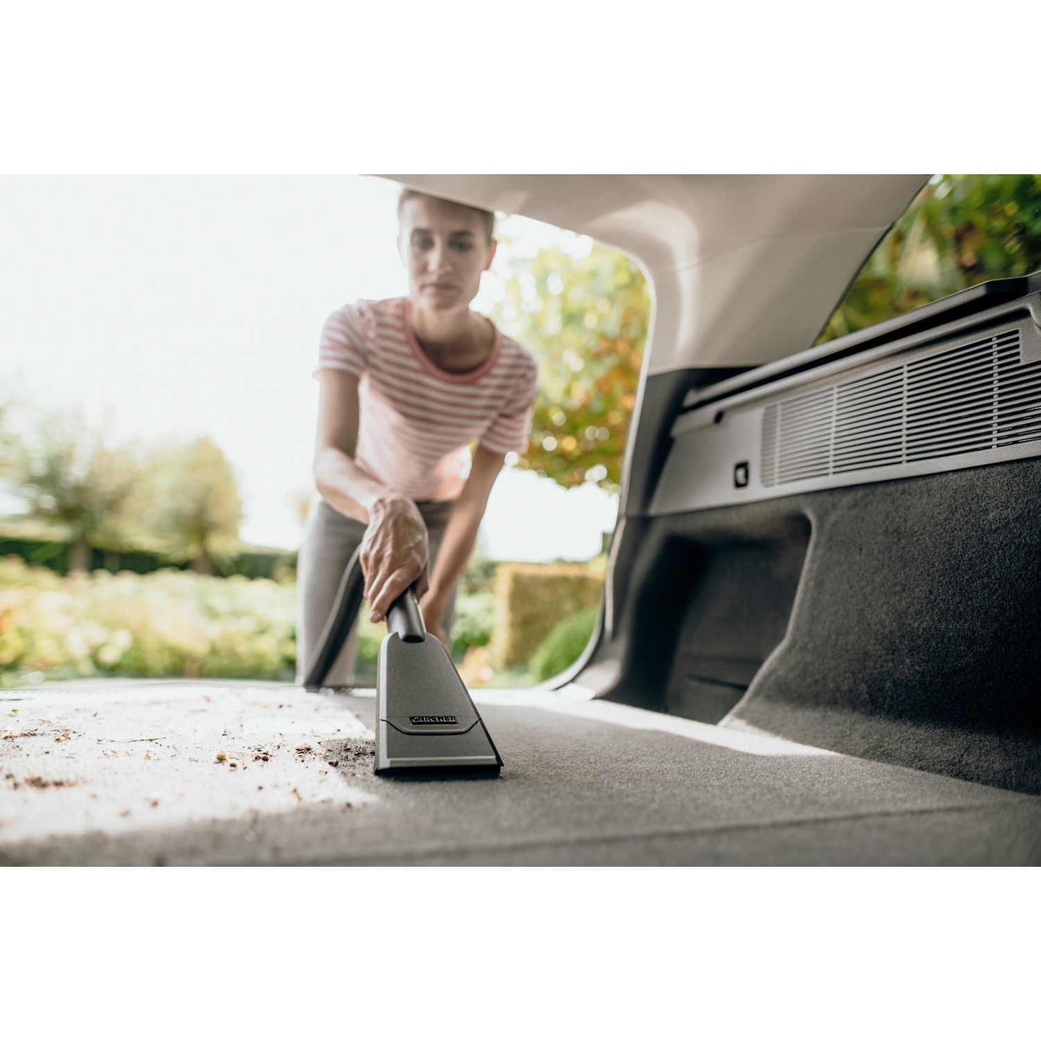 Frau saugt mit Kärcher Autodüse Kofferraum. Nass-/Trockensauger Zubehör für Auto & Haushalt.