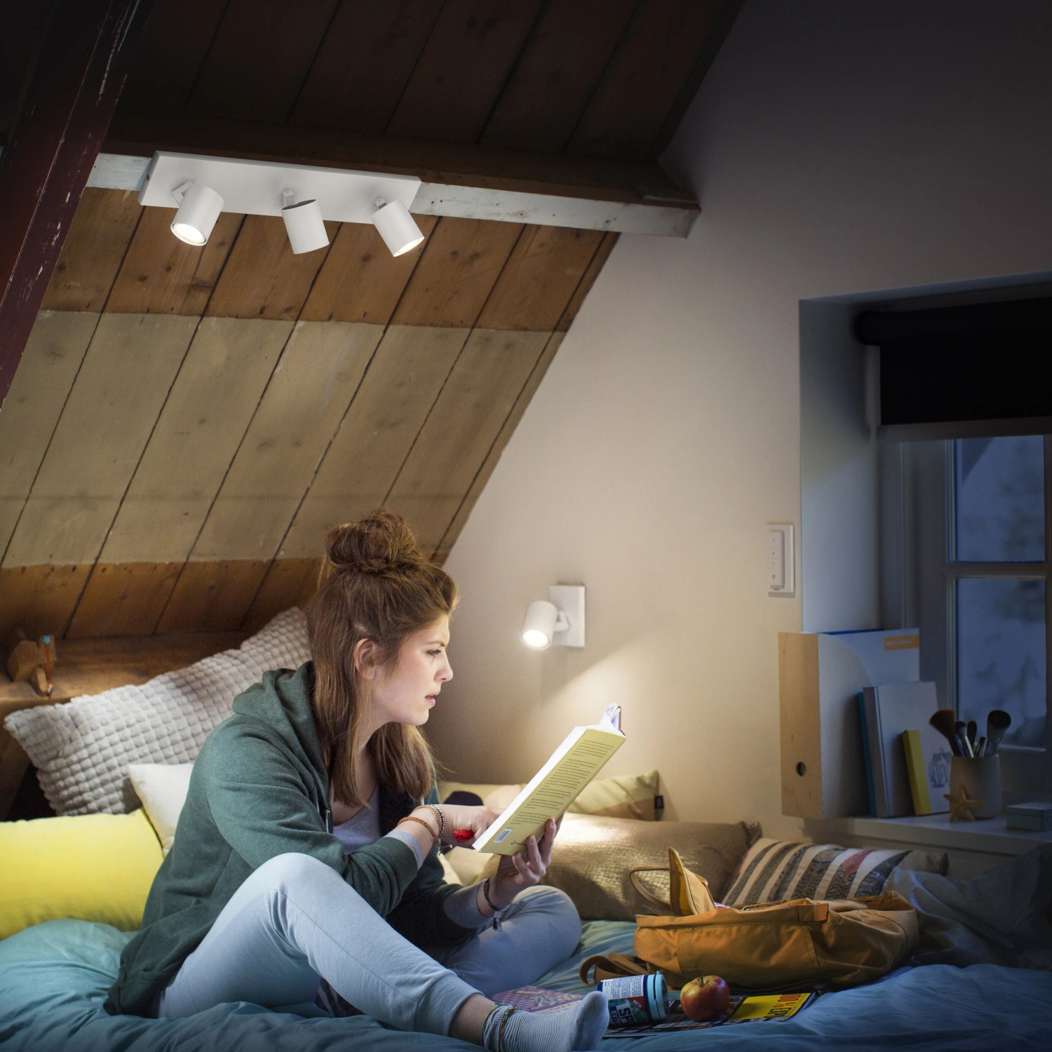 Philips Hue Runner: 3-flammiger LED Spot in Weiß, mit Dimmer. Szene: Junge Frau liest im gemütlichen Licht.