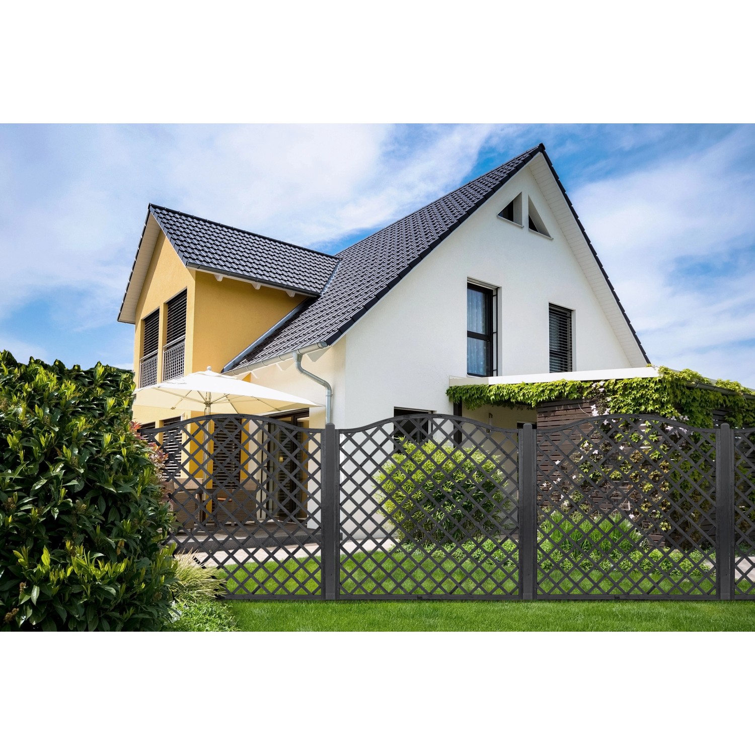Anthrazitfarbener Sichtschutzzaun Nancy aus Holz vor einem Haus mit Garten.