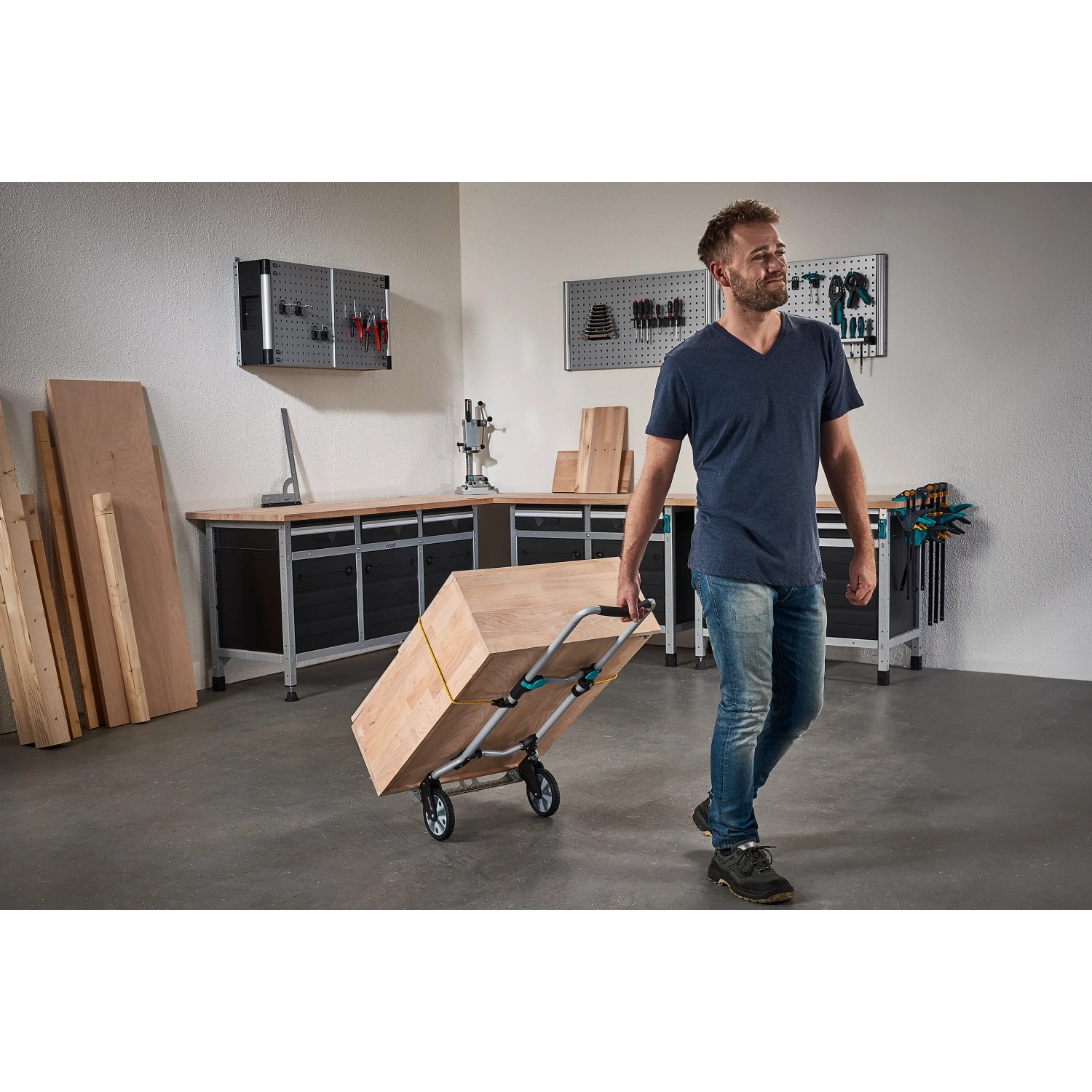 Mann transportiert Holz mit klappbarer wolfcraft Sackkarre TS 600 in Werkstatt.
