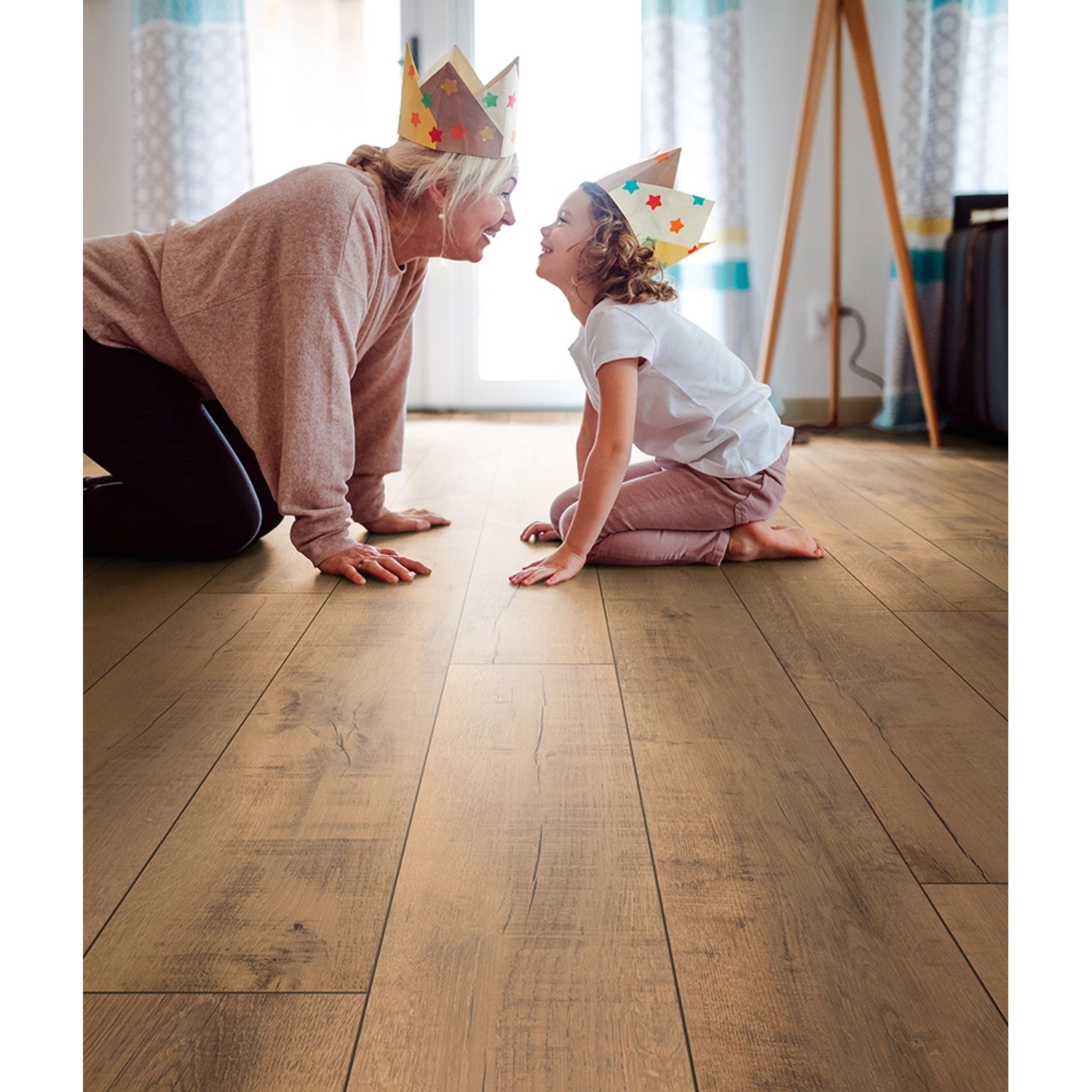 Verlegter Laminatboden Kronoflooring Gold Volcano Oak mit spielender Familie im Wohnraum.