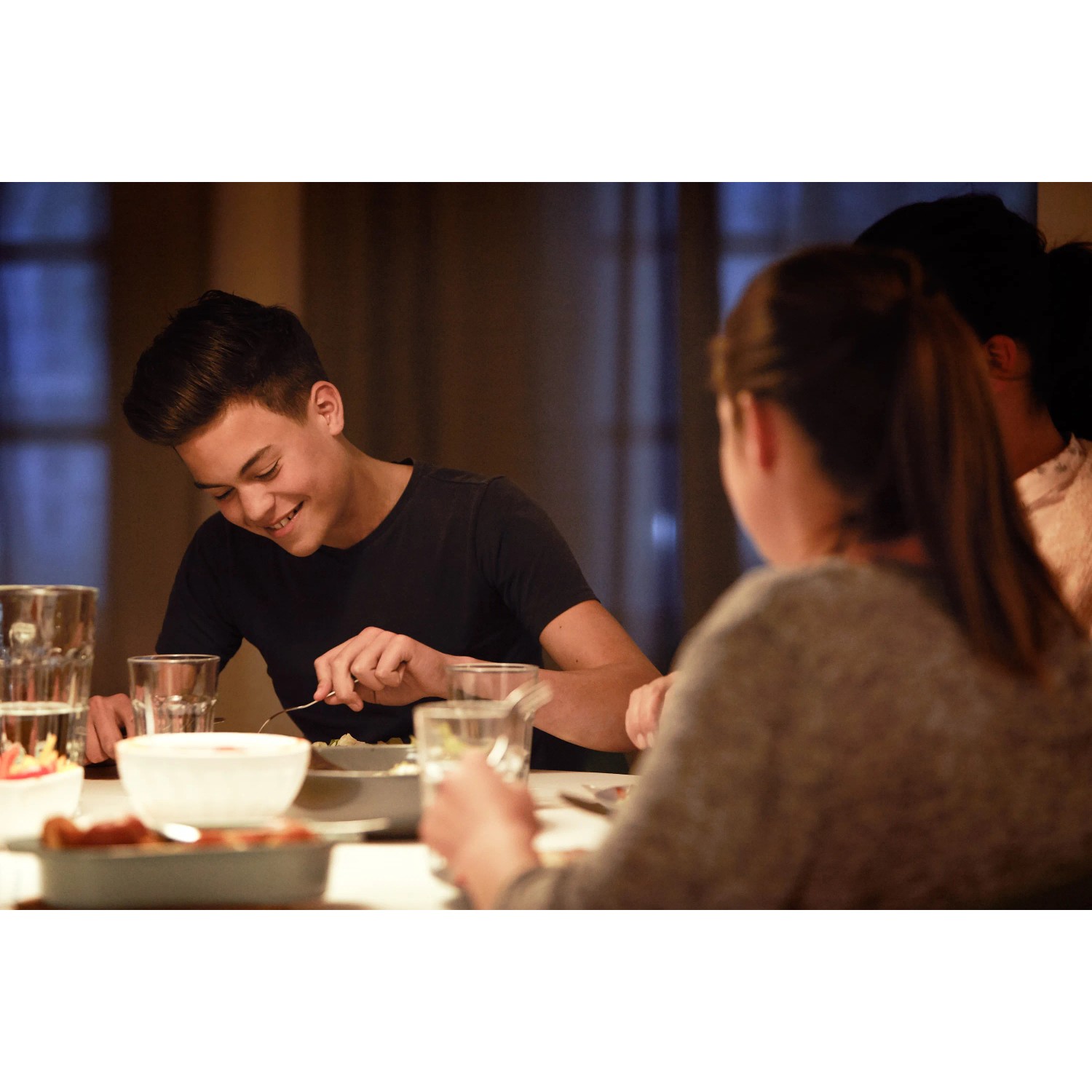 Szene mit warmweißem Licht einer Philips E14 LED Reflektorlampe beim Abendessen mit Freunden.