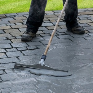 Verfugung von Pflastersteinen mit Tassullo Pflasterfugenmörtel, aufgetragen mit Gummischieber.