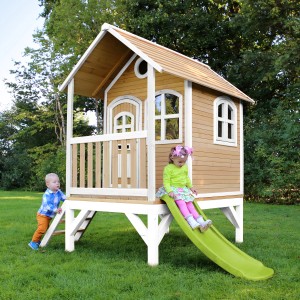 Axi Tom Spielhaus aus Holz in Braun-Weiß mit lindgrüner Rutsche und spielenden Kindern im Garten.