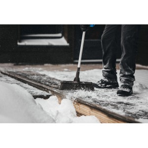 Fiskars Besen Light beim Schneekehren auf einer Holzterrasse.