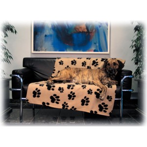 Beige Jollypaw Fleecedecke Janno (150x100 cm) mit schwarzen Pfotenabdruck auf Sofa mit Hund.