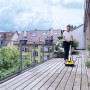 Frau reinigt Terrasse mit Kärcher PCL 4 Flächenreiniger. Elektrischer Terrassenreiniger für Holz- und Steinflächen.