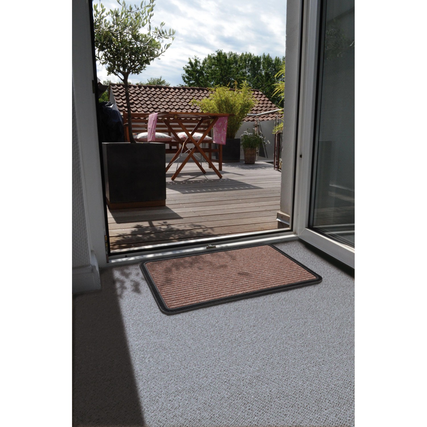 Braune Astra Fußmatte Border Star, 50x80 cm, vor einer Terrassentür.