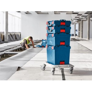 Gestapelte blaue Bosch Professional L-Boxx Werkzeugkoffer auf Rollbrett im Rohbau.