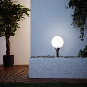 Weiße LED-Gartenleuchte Thore von Brilliant, 8W, im Beet. Dekorative Außenbeleuchtung mit Erdspieß.