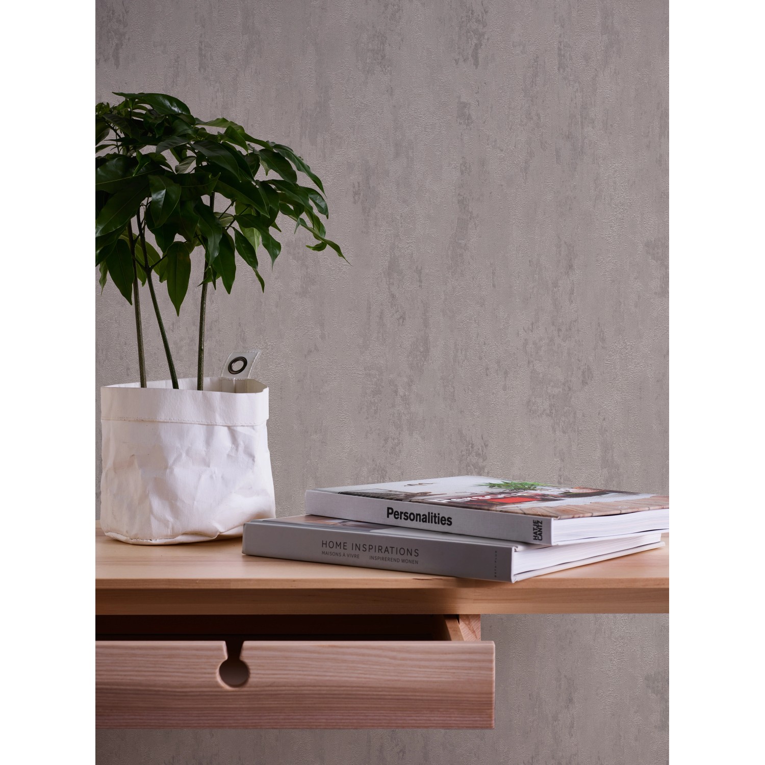 Vliestapete Trendwall 2 Uni Grau Silber Glänzend an Wand, mit Pflanze und Büchern auf Tisch.