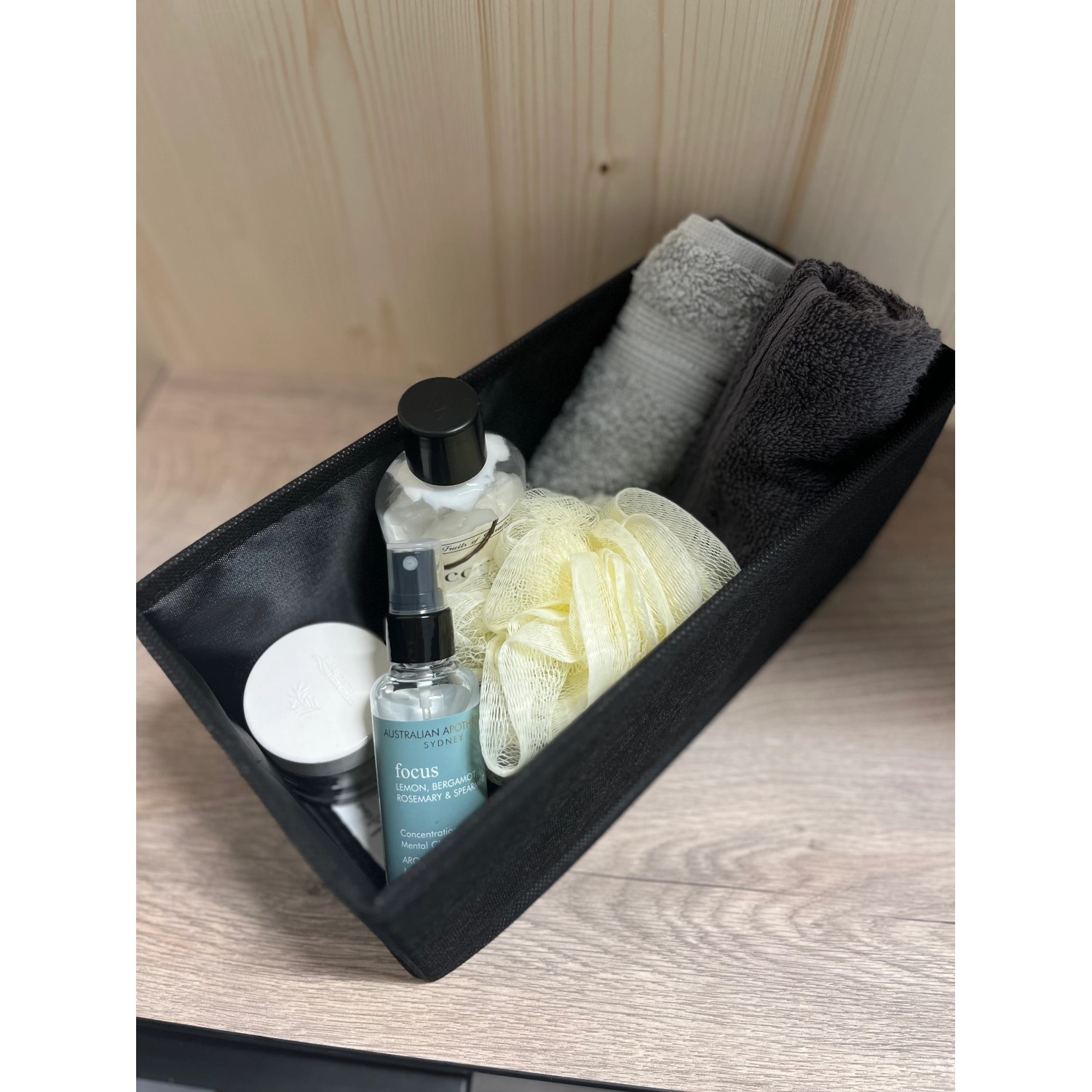 Schwarzes Fackelmann Universalkörbchen Textil (13x12x28cm) mit Badartikeln wie Handtücher und Kosmetik.