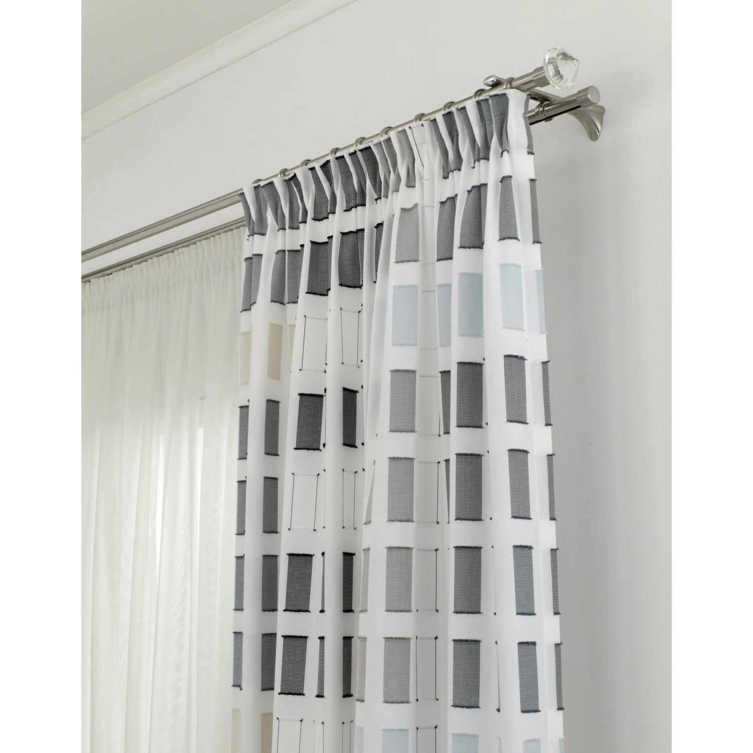 Gardinenstange Chicago mit Endstücken in Edelstahloptik und Vorhang mit grafischem Muster.