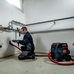 Handwerker bohrt mit Metabo Kombihammer KHE 2445 in Wand, inkl. Staubsauger. Bohrhämmer für Stein und Beton.