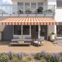 Beige-rot gestreifte Gelenkarmmarkise Wismar Classic, 300x200 cm, montiert an einer Hauswand über einer Terrasse.