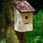 Holz Nistkasten mit braunem Rindendach am Baum befestigt.