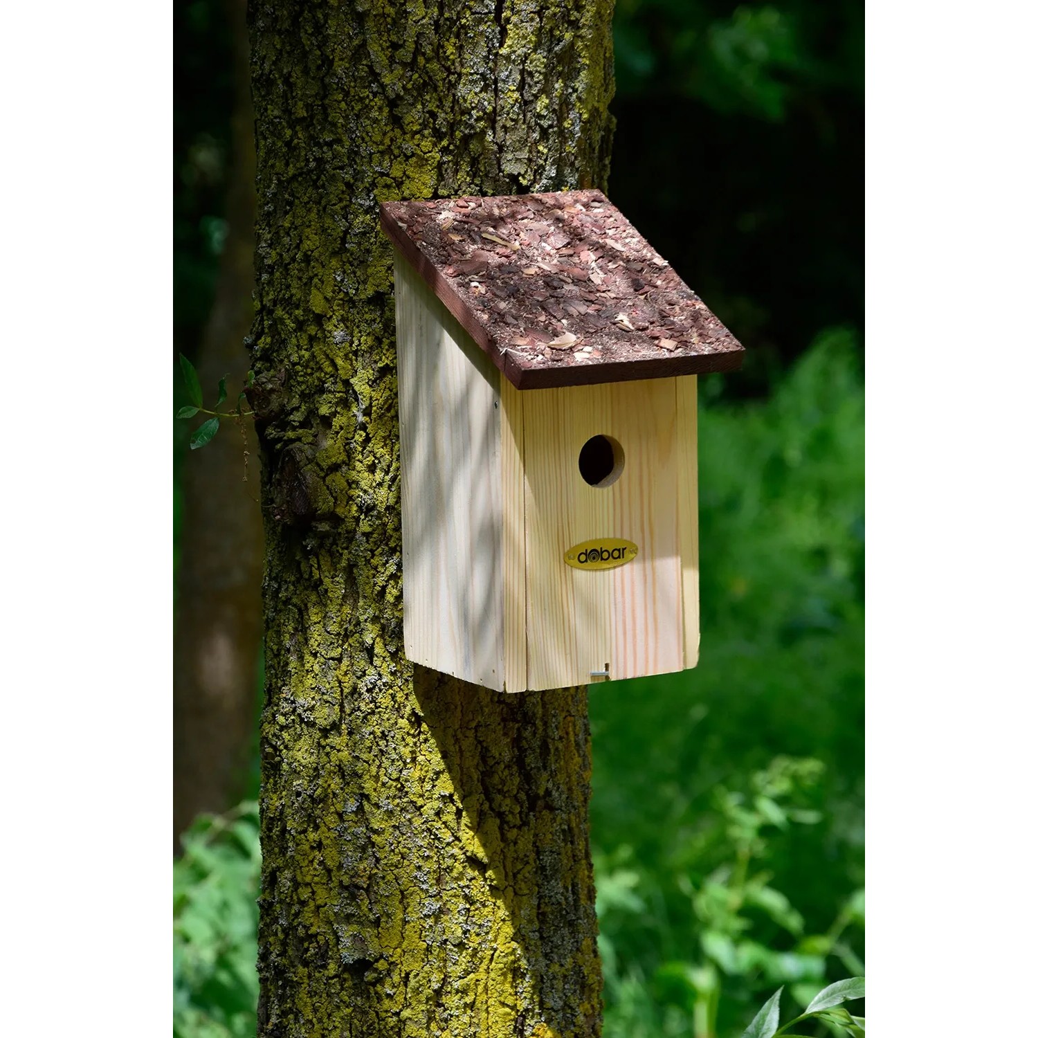 Holz Nistkasten mit braunem Rindendach am Baum befestigt.
