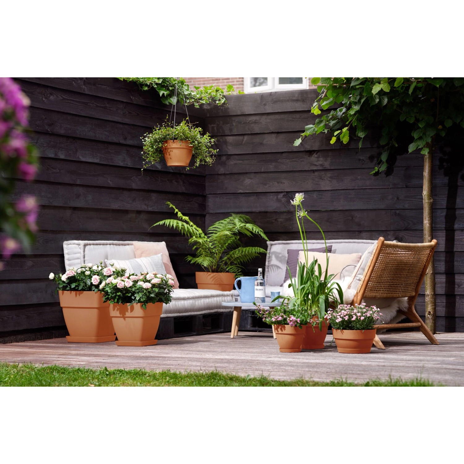 Elho Blumentopf Vibia Campana, Ø 34cm, Terrakotta, mit Pflanzen auf einer Terrasse.