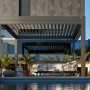 Moderne, dunkelgraue Biohort Pergola mit Lamellen und Sitzgruppe am Pool.