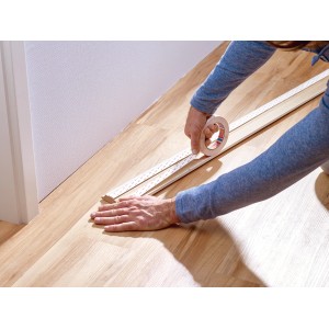 Anwendung von Tesa Montageband für Tapeten und Putz auf einer Holzleiste.