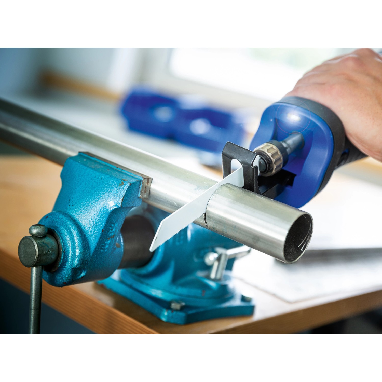 LUX Säbelsäge E-SBS-21 schneidet Metallrohr im Schraubstock. Stichsäge mit LED-Arbeitsleuchte.