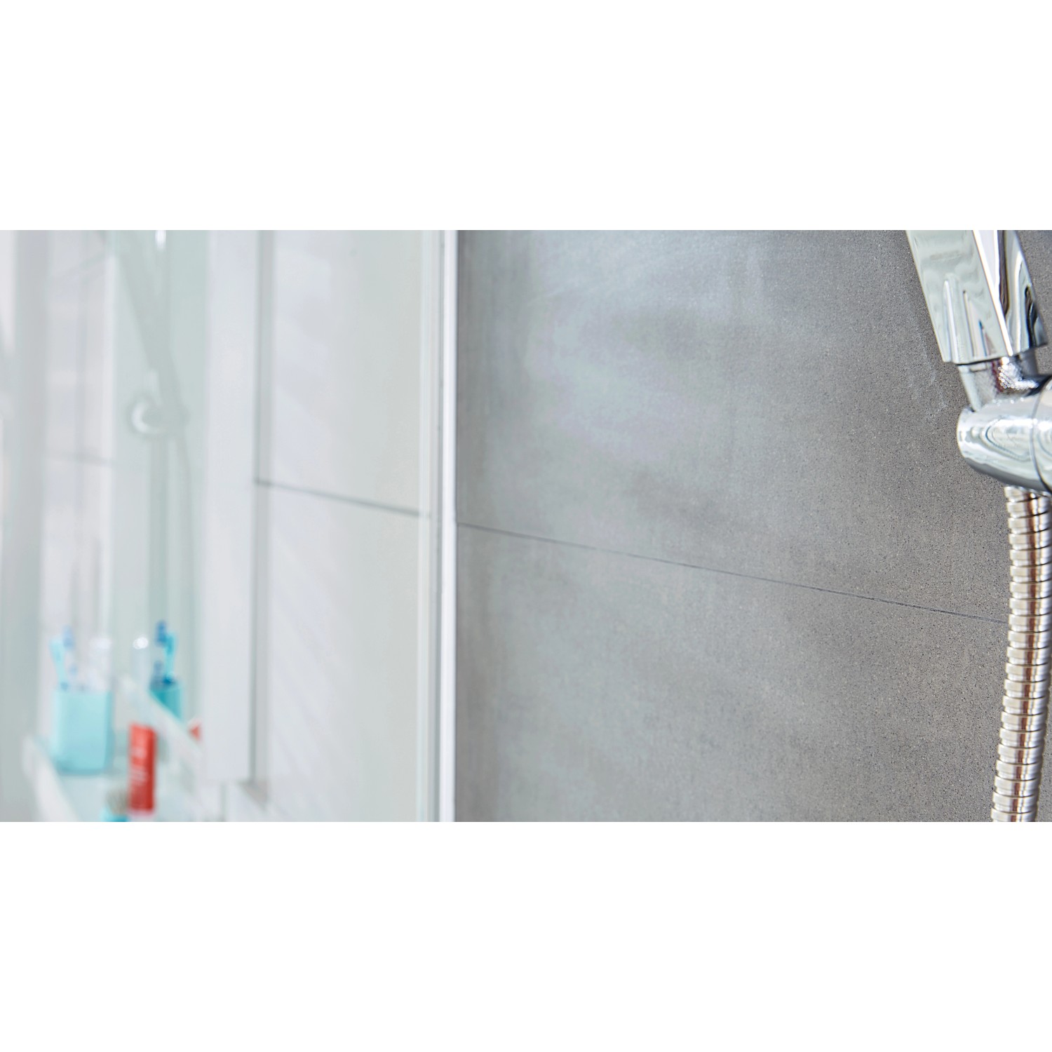 Tesa Powerstrips Haken Waterproof Zoom Edelstahl Small, 2er-Pack, an grauer Wand neben Dusche.