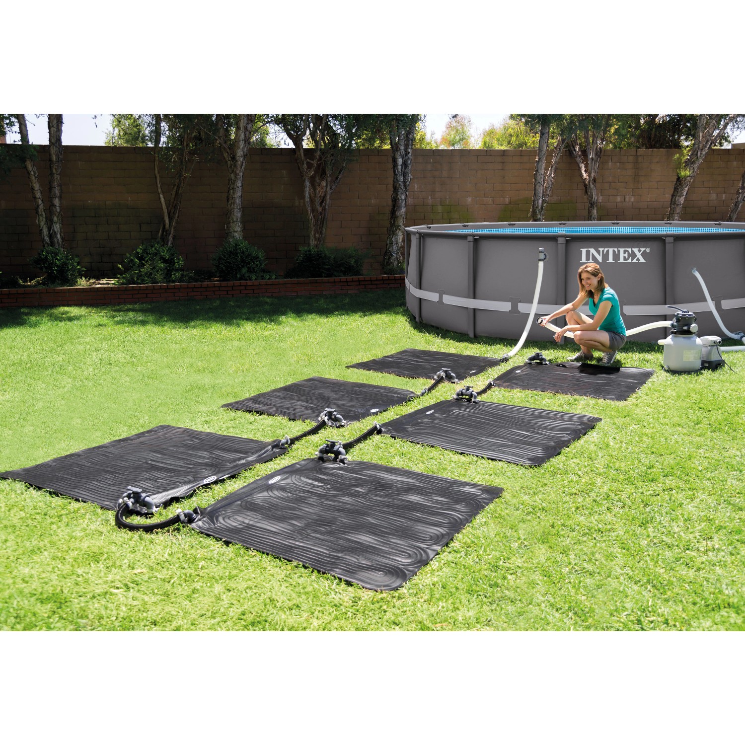 Intex Solarmatte 120x120 cm zur Poolwasser-Erwärmung im Garten mit Pool und Frau.