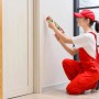 Frau dichtet Fugen am Türrahmen mit weißem Soudal Maleracryl aus der Kartusche ab. Acryl-Dichtmasse für Innenbereich.