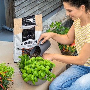 Frau befüllt Pflanztopf mit Lechuza Pon Schütte in Schiefergrau. Zubehör für Pflanztöpfe.