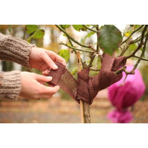 Dunkelbraunes Videx Garden Deko-Juteband wird um einen Baumstamm gewickelt.