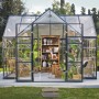 Palram Canopia Victory Orangerie Gewächshaus mit Bücherregal und Pflanzen im Garten.
