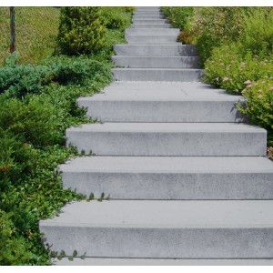 Treppe mit grauen Blockstufen (100x35x15 cm) im Außenbereich, umgeben von Grünpflanzen.